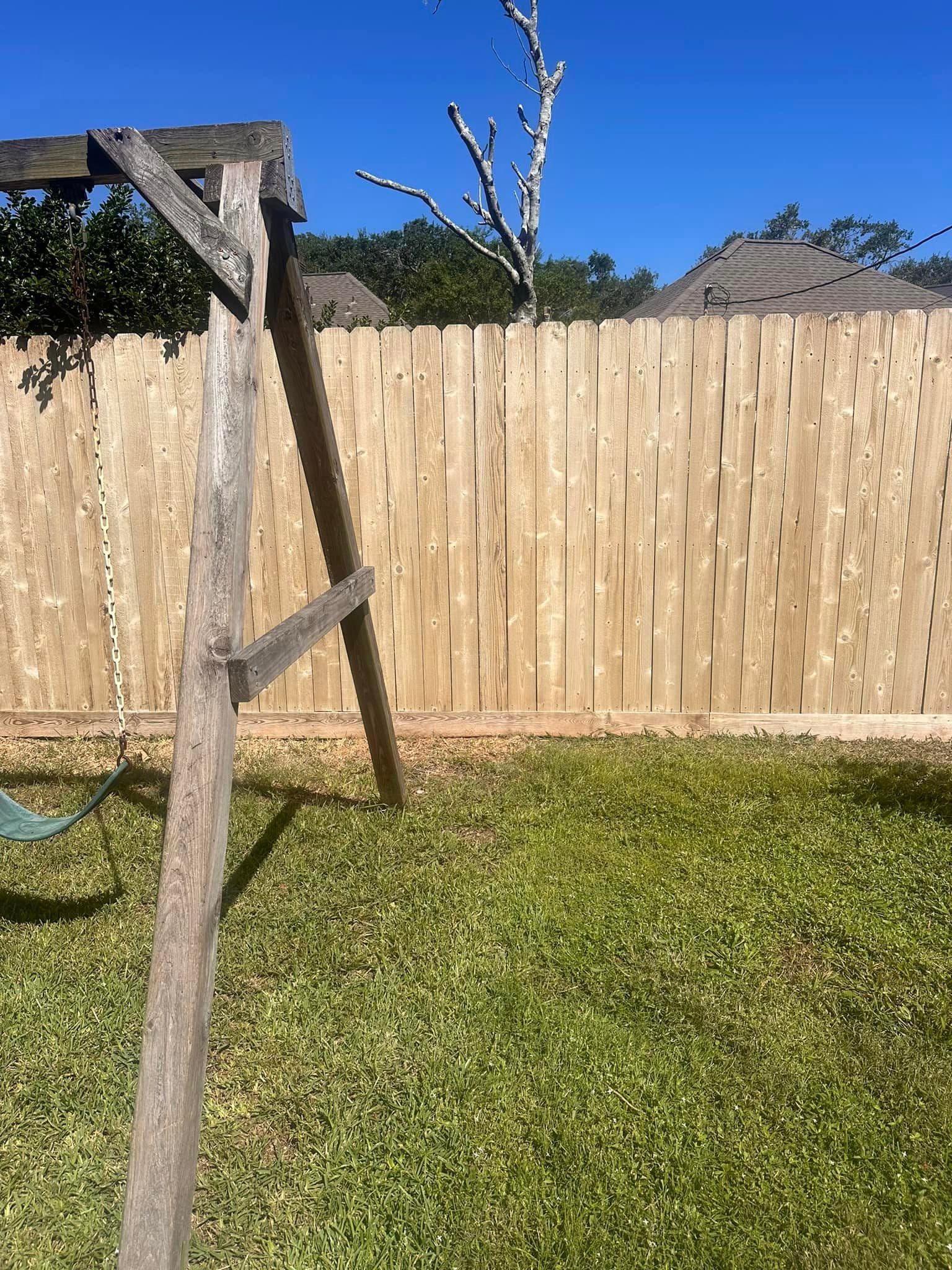 A wooden fence after cleaning, showing restored natural wood color along the full run