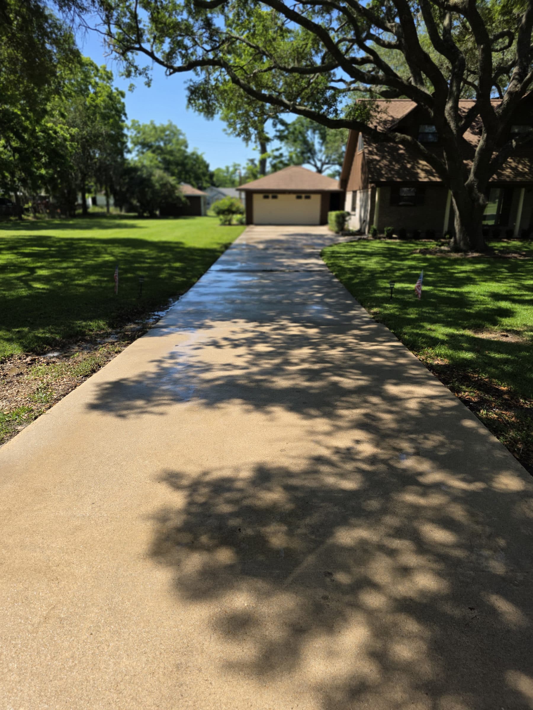 A rotating surface cleaner working across a concrete driveway, leaving an even finish behind it